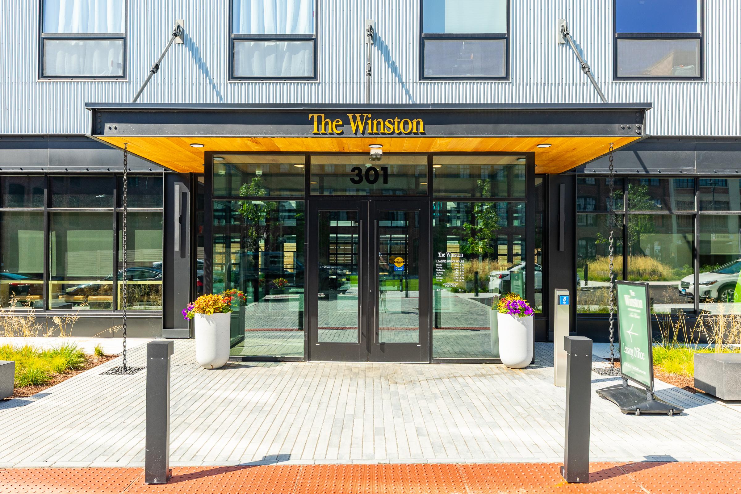 The Winston Glass entrance canopy of The Winston building with its address sign and planters