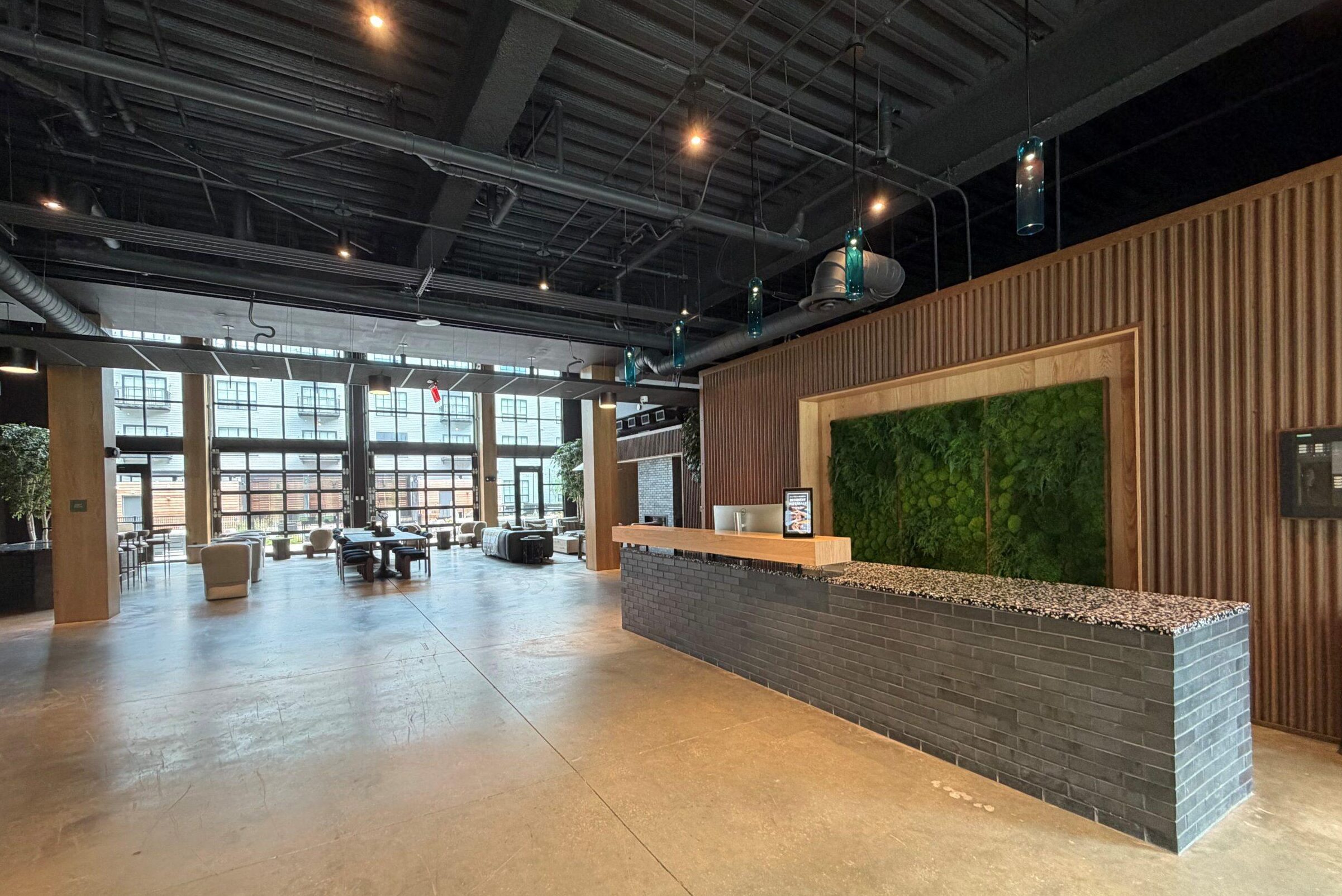 Lounge at The Winston Apartment community lounge with wood-slat walls, a kitchenette bar, and lounge seating on a concrete floor