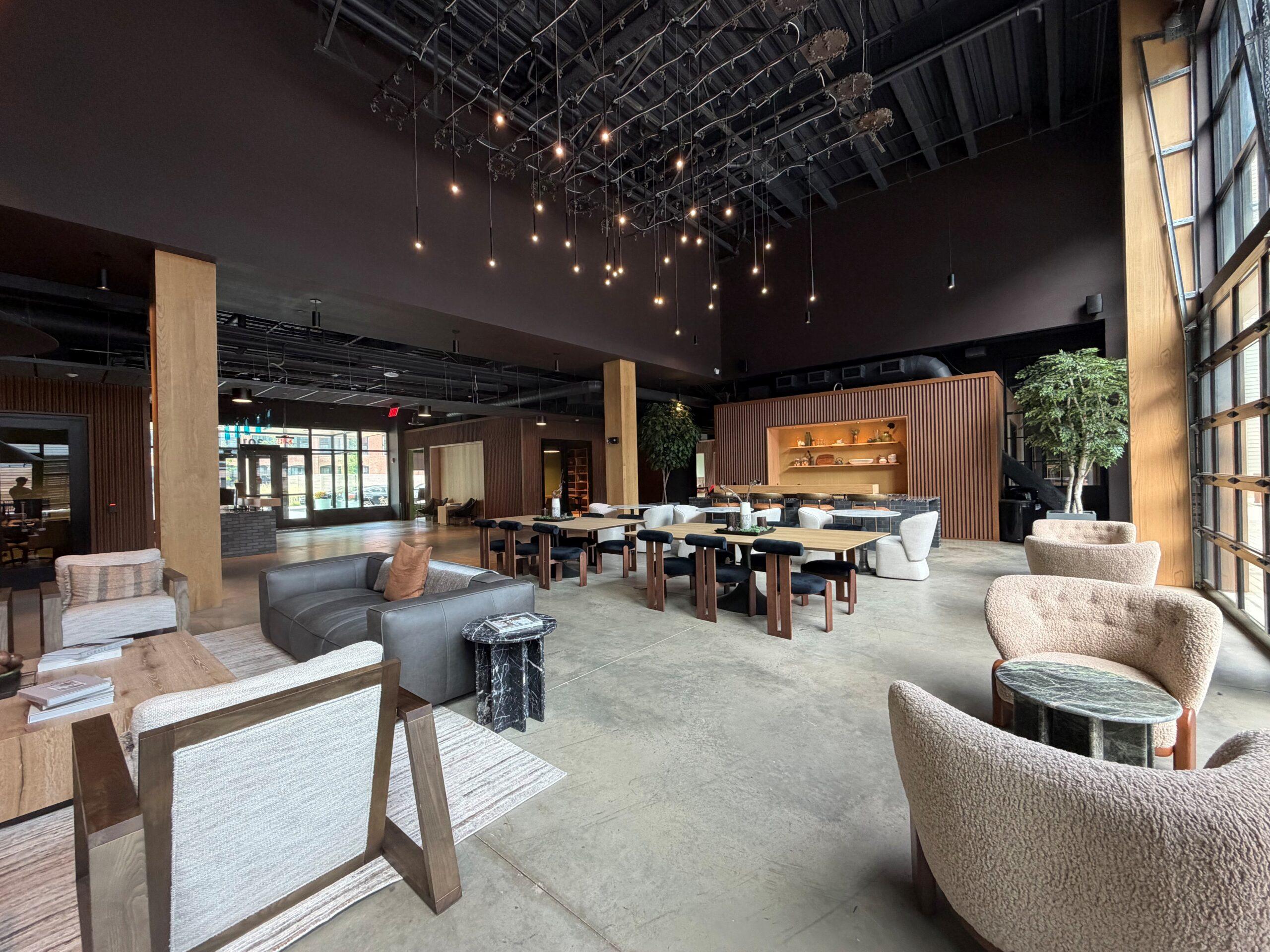 Lounge at The Winston with tables and chairs Apartment community lounge with cluster pendant lights, sofas, communal tables, and large windows