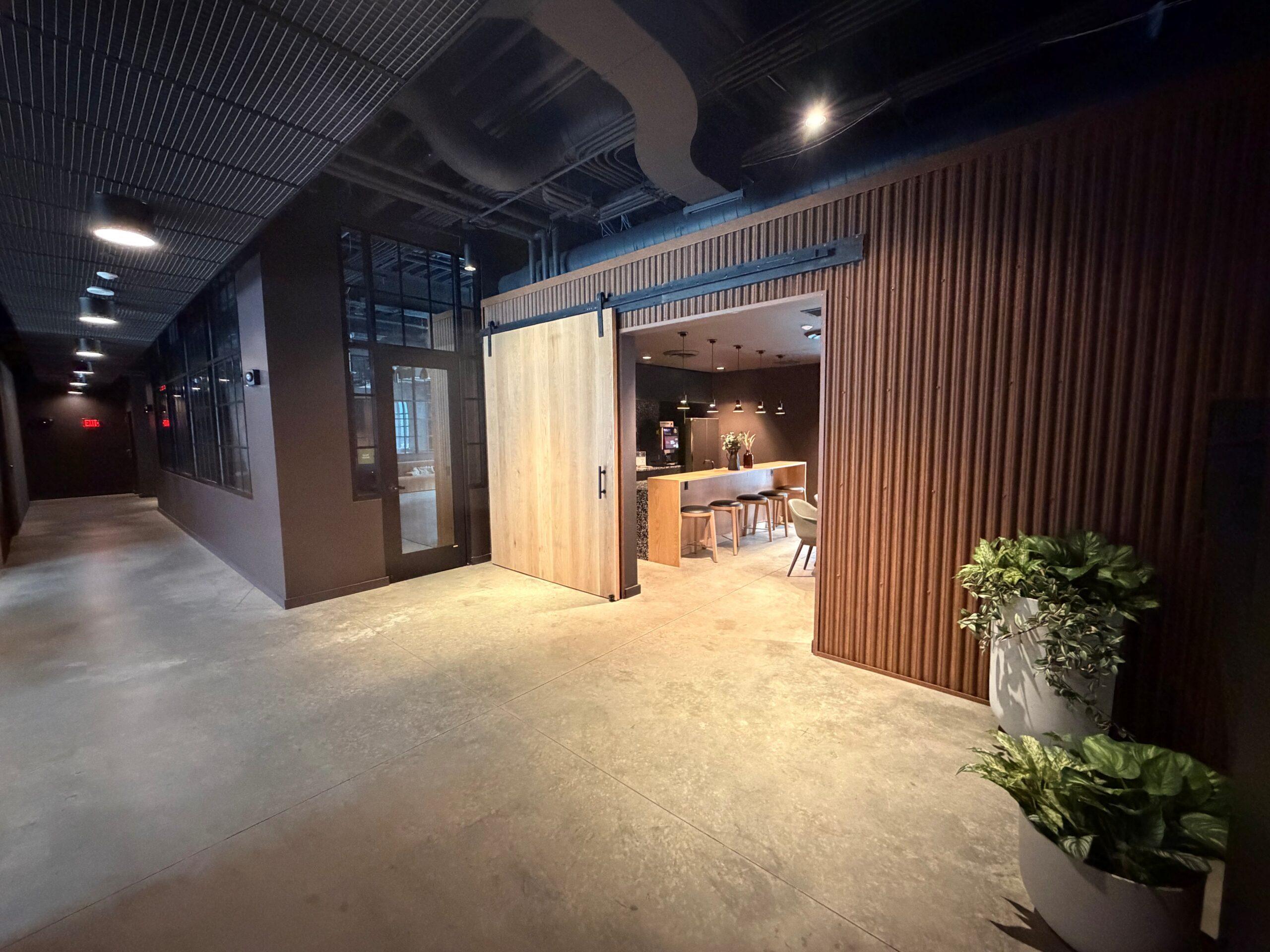 Corridor at The Winston Apartment amenity corridor with a wood-slat wall leading to a modern kitchen and lounge