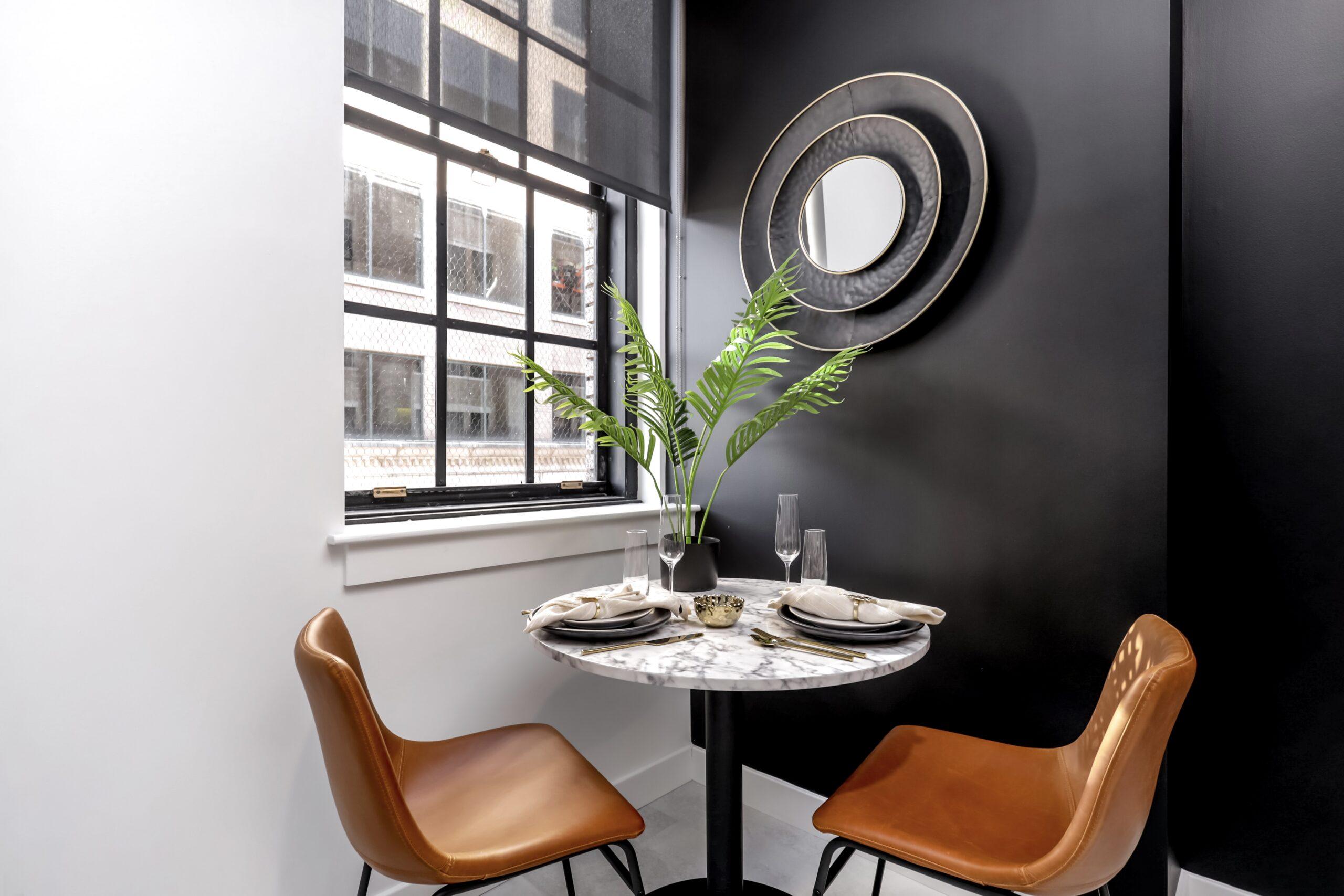 Dining area at 99 State Street Loft apartment dining nook with a round marble table, leather chairs, a sunburst mirror, and industrial windows