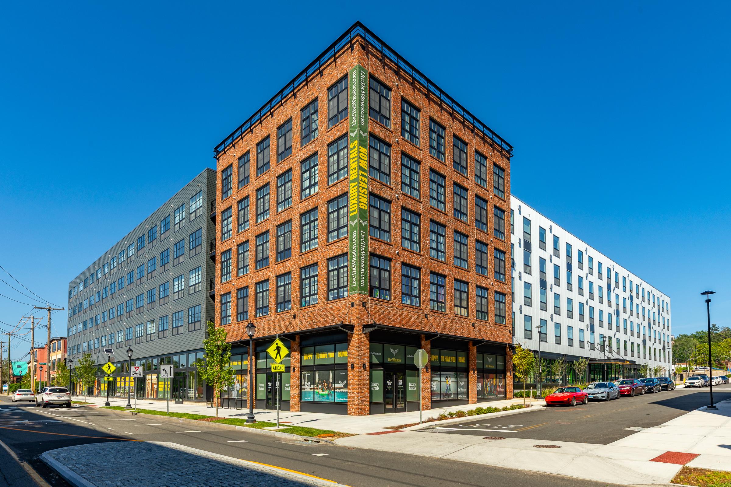 The Winston building Corner exterior of a modern brick apartment building with ground-floor retail