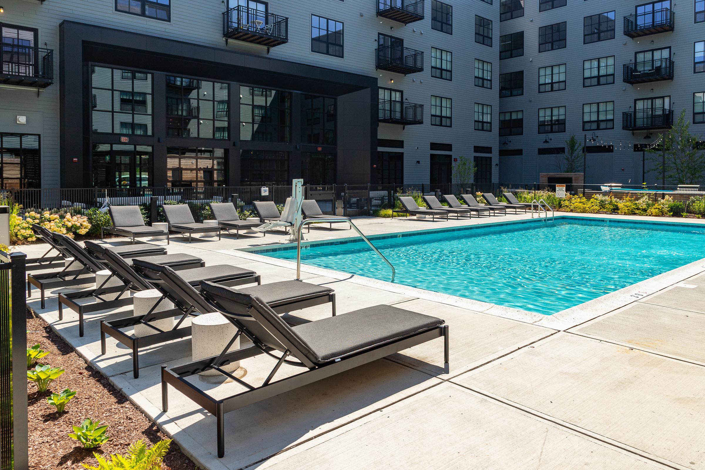 The Winston pool and lounge chairs Apartment pool deck with lounge chairs and umbrellas beside the building