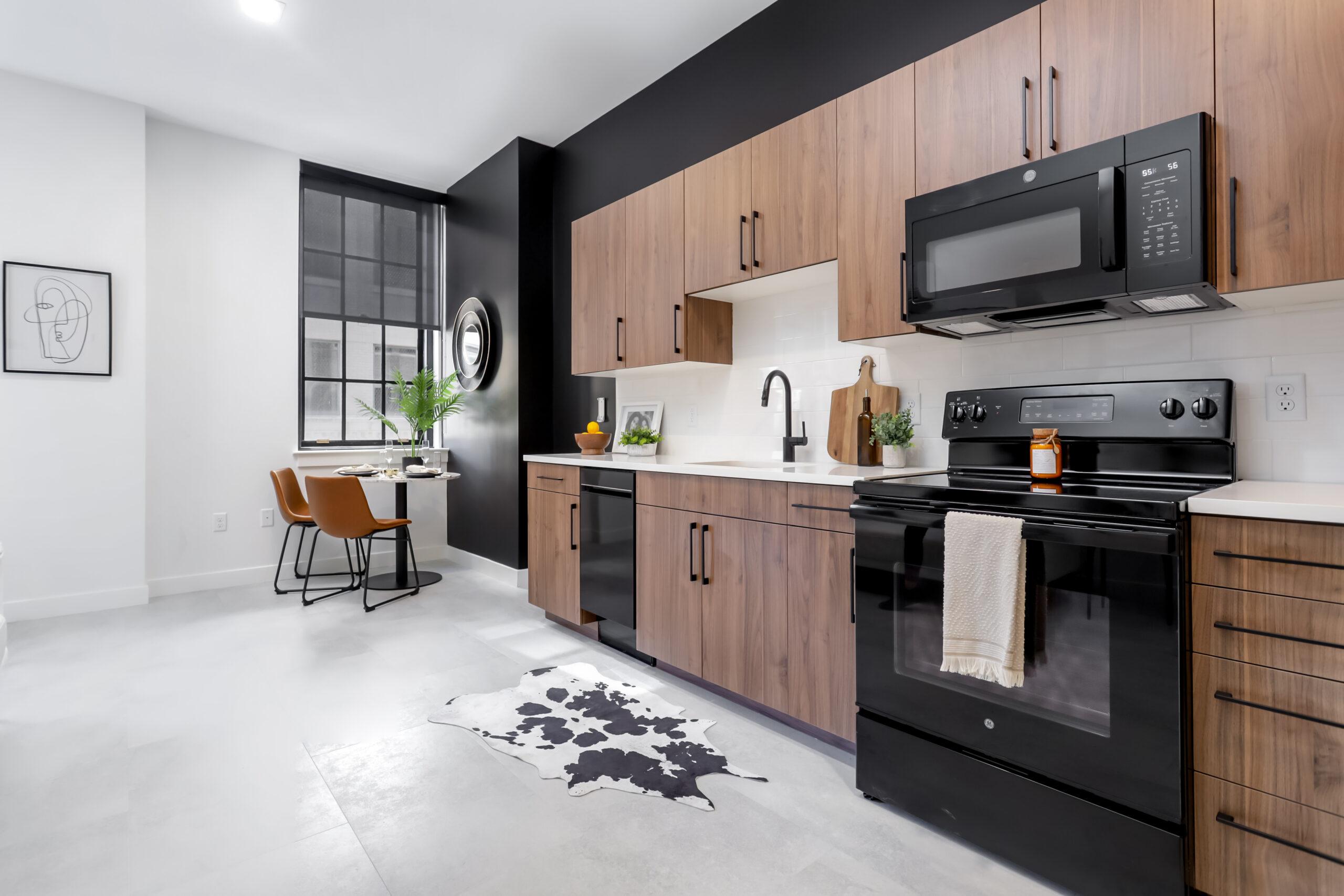Kitchen at 99 Pratt Street Apartment kitchen with wood cabinets, a black range and microwave, a round mirror, and a cowhide-pattern rug